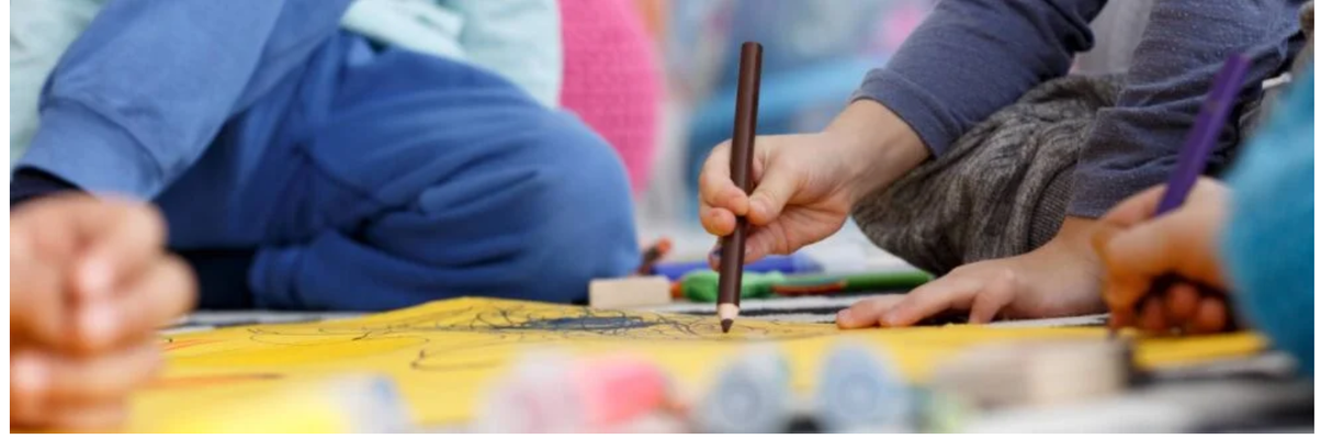 Little children drawing together with crayons at kindergarten